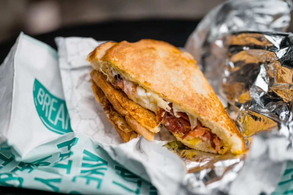 Toasted sandwich with bacon and cheese on a to-go wrapper