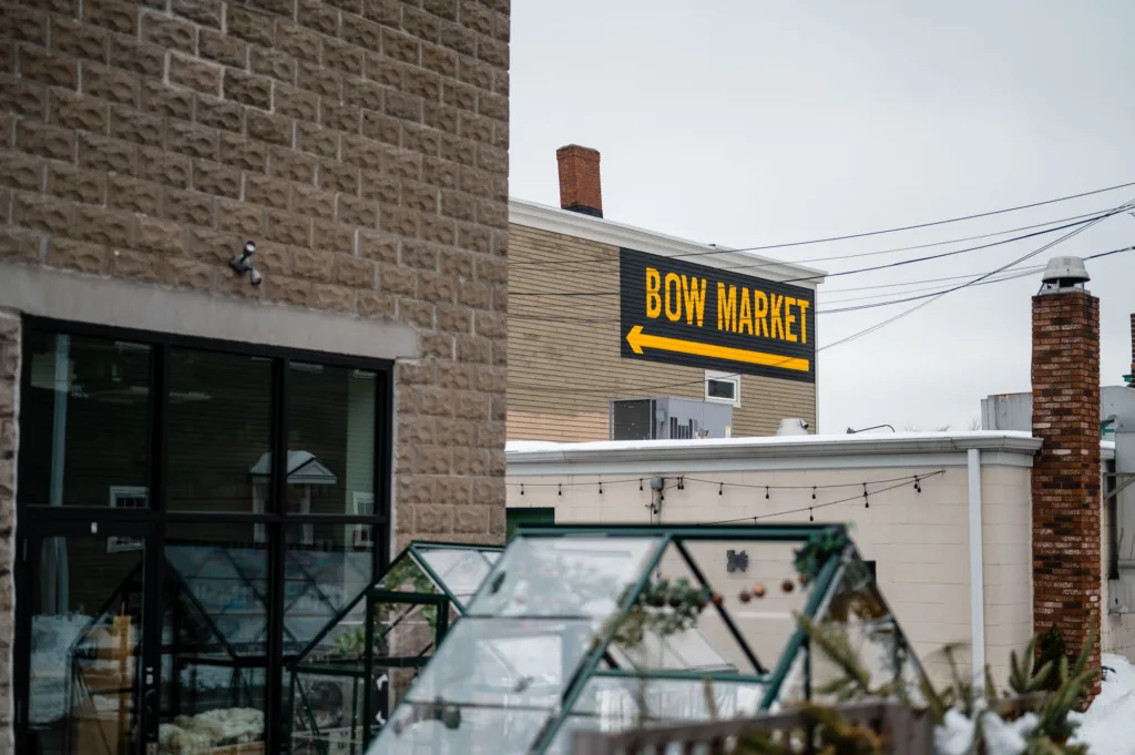 Large painted sign on a building pointing to Bow Market in Somerville, MA