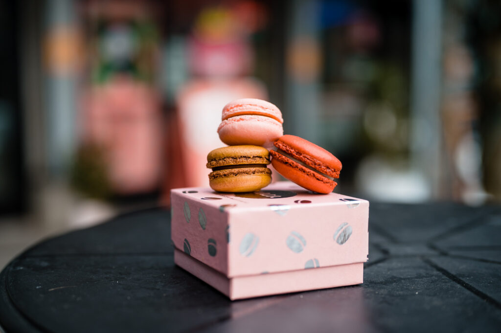 Three colorful macarons sitting in a neat pile on a small pink box