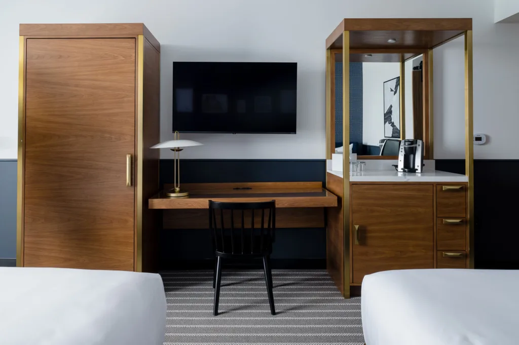 Somerville hotel room with two dressers, two beds, a desk, and a TV