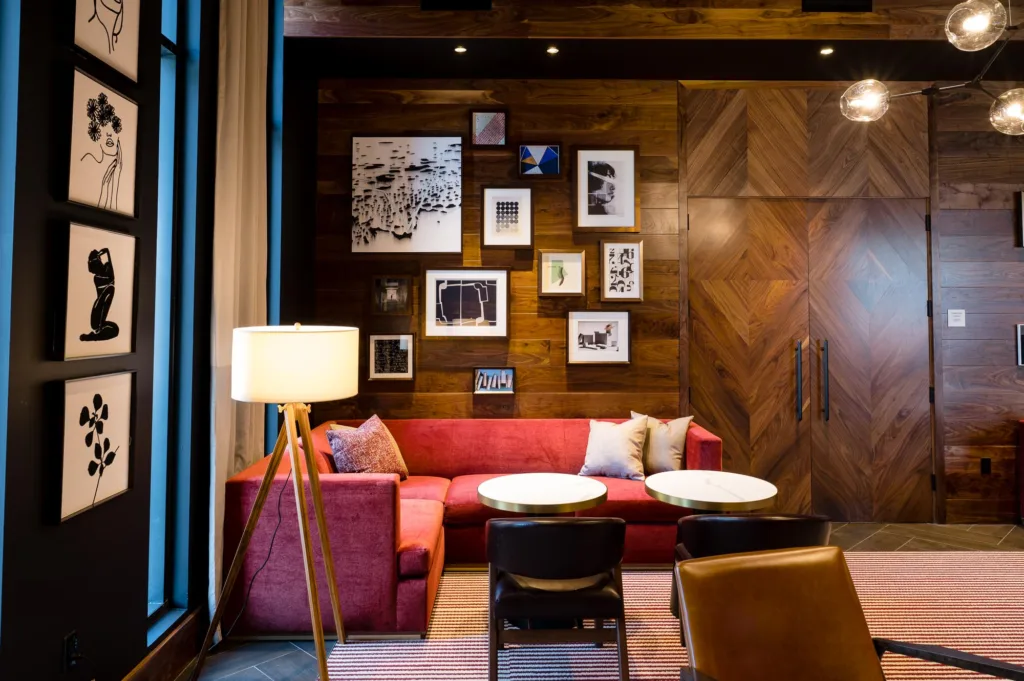 Red corner sofa and wall art in a lounge area at Cambria in Somerville, MA