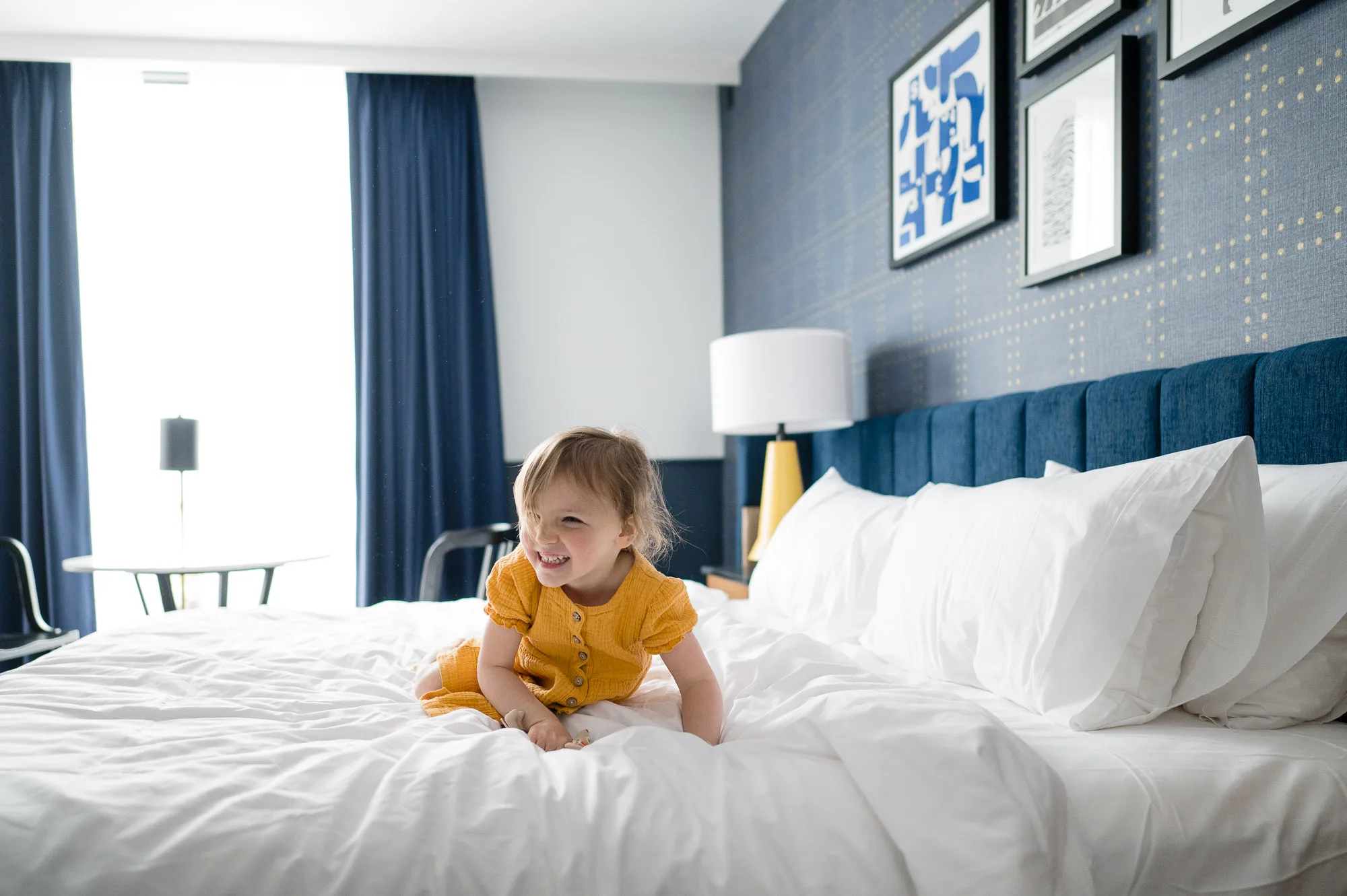 a child on hotel bed at Cambria hotel in Somerville