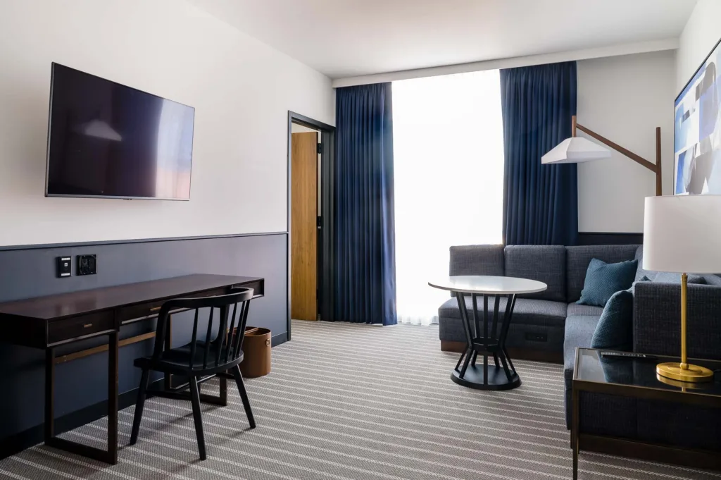 Hotel living area at Cambria Somerville with a large corner sofa and desk
