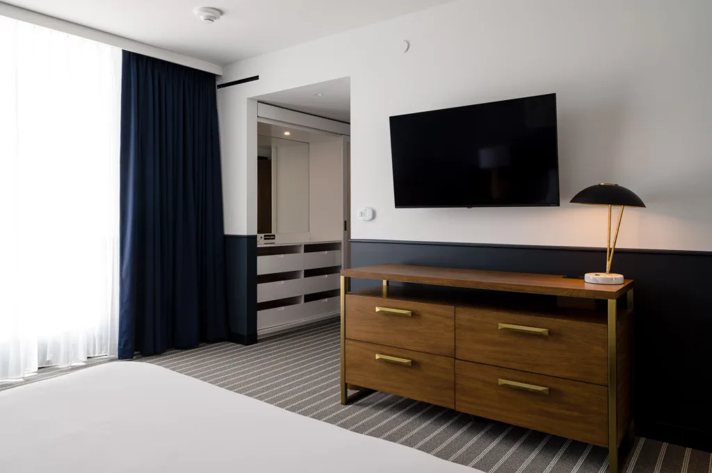 Large TV over a dresser in a hotel room at Cambria Somerville in MA