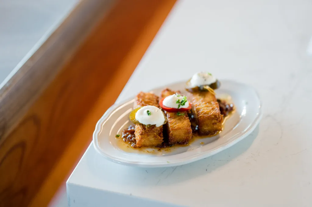 Plate of fried bites topped with cream at Cambria Hotel Boston-Somerville