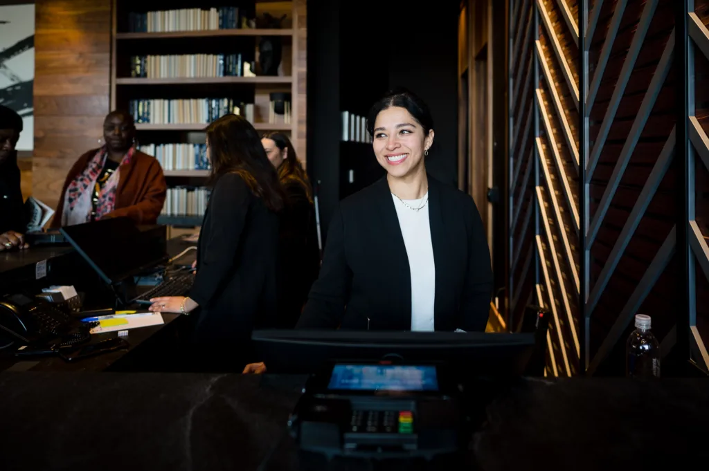 Front desk staff smiling at the reception area of Cambria Hotel Boston-Somerville