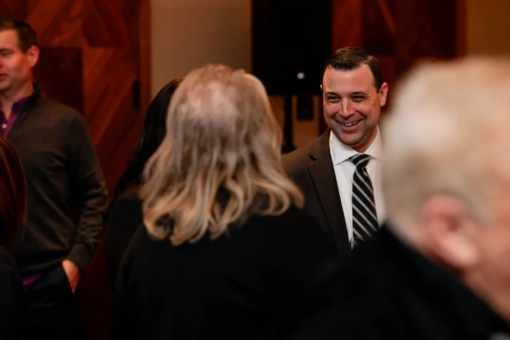 Guests smiling and talking during an event at Cambria Hotel Boston-Somerville