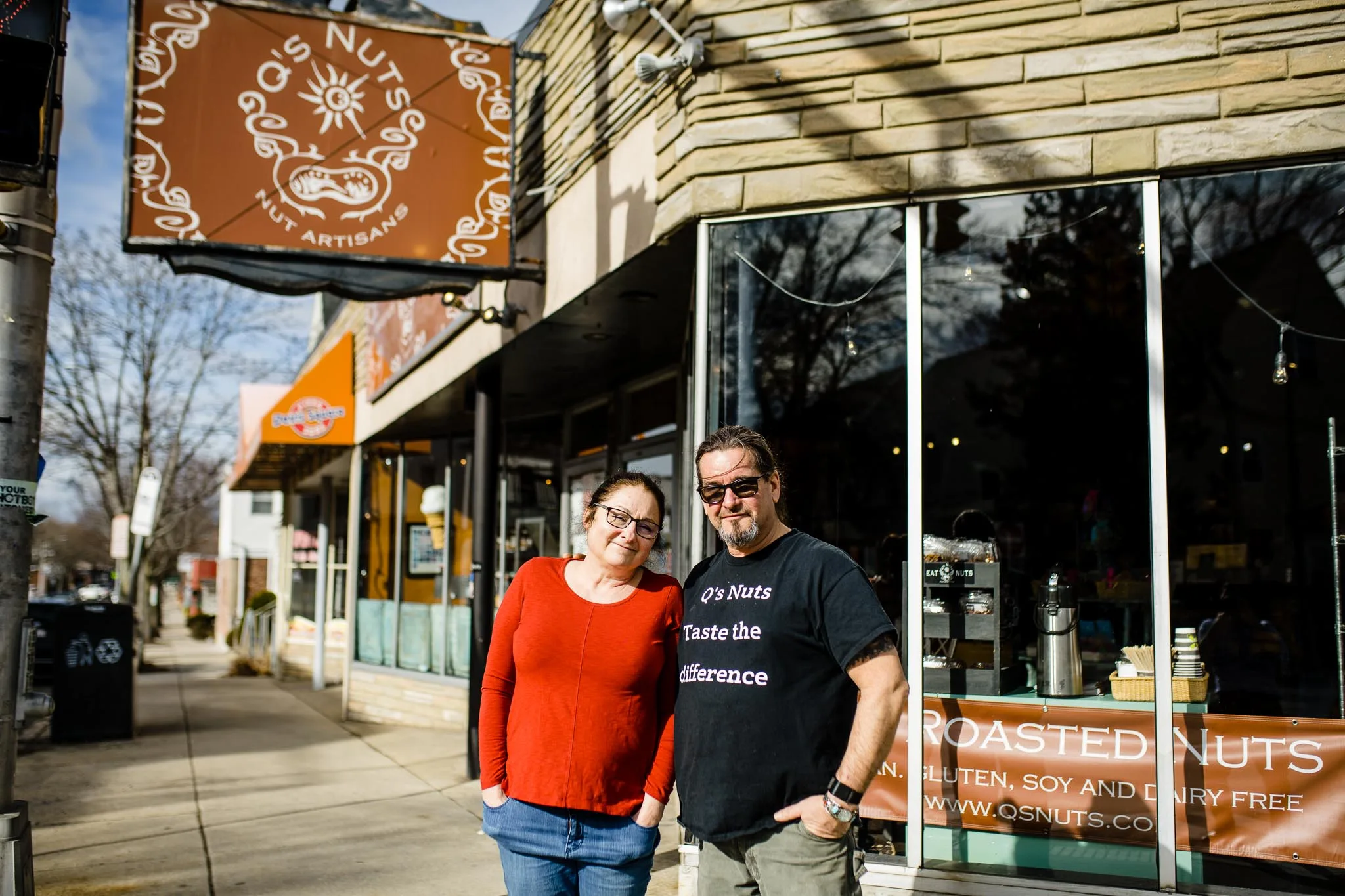two people posing outside q's nuts storefront